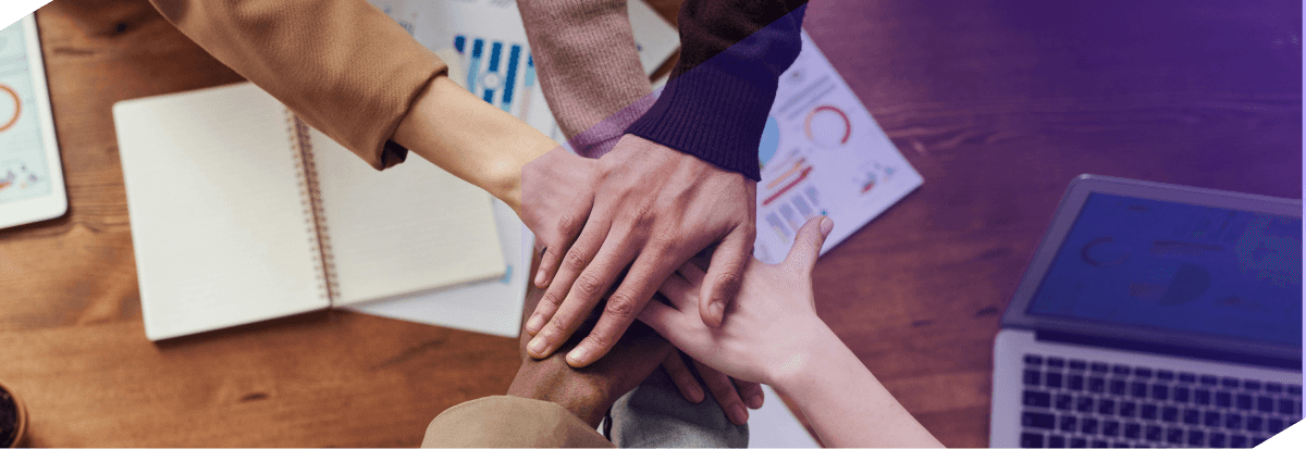 Team members connecting hands together over documents